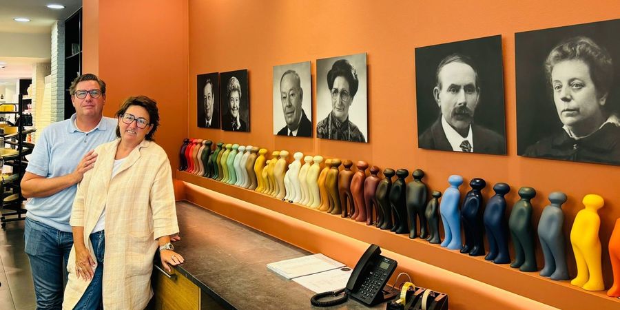 Jan Bisschop en zijn vrouw Peggy bij portretten van de vorige zaakvoerders van het familiebedrijf